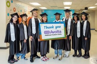 Small group of students wearing graduation gowns and caps hold a sign that reads "Thank you, Avolta"