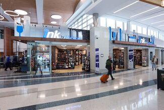 A man with an orange suitcase walks in front of a bookstore in the airport